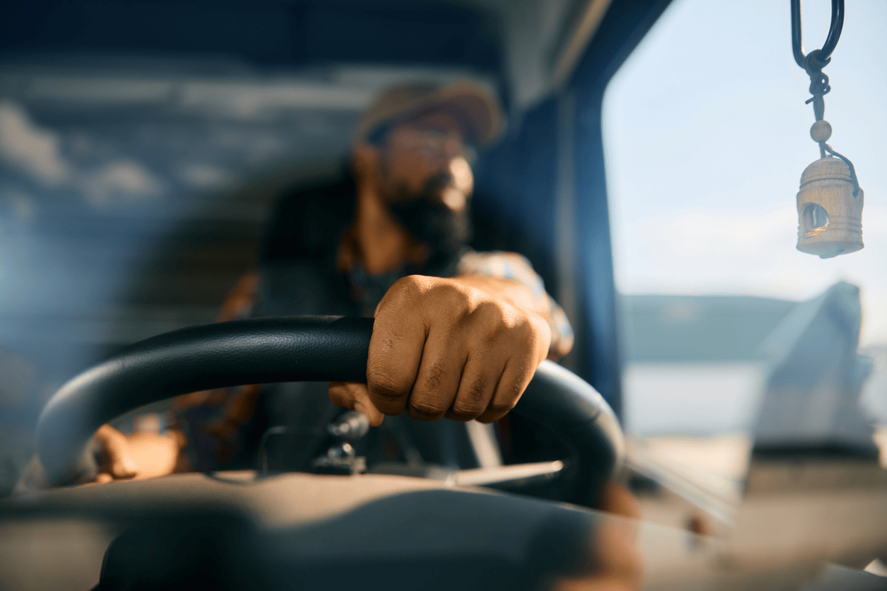 truck driver’s hand gripping the steering wheel while driving.
