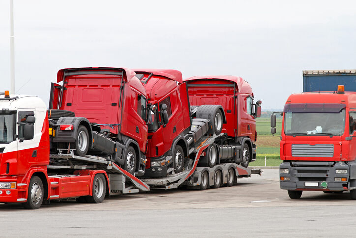 Trucks being loaded onto a transport vehicle, illustrating the potential hazards of debris causing secondary accidents.